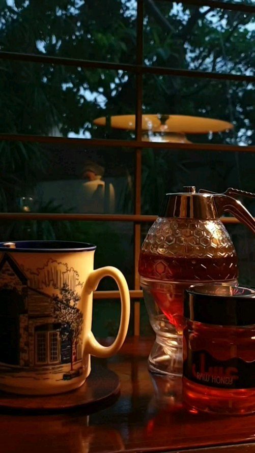 A cup of tea with a spoonful of honey going in.