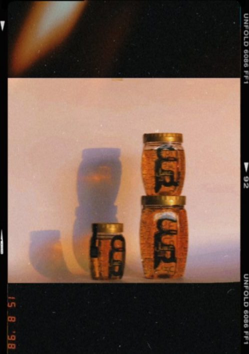 Three sizes of Asal jar photographed on film against a blush backdrop, gold lids catching the light.